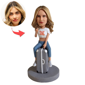 Figurine à tête branlante personnalisée posée sur une valise