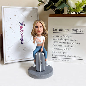 Figurine à tête branlante personnalisée posée sur une valise