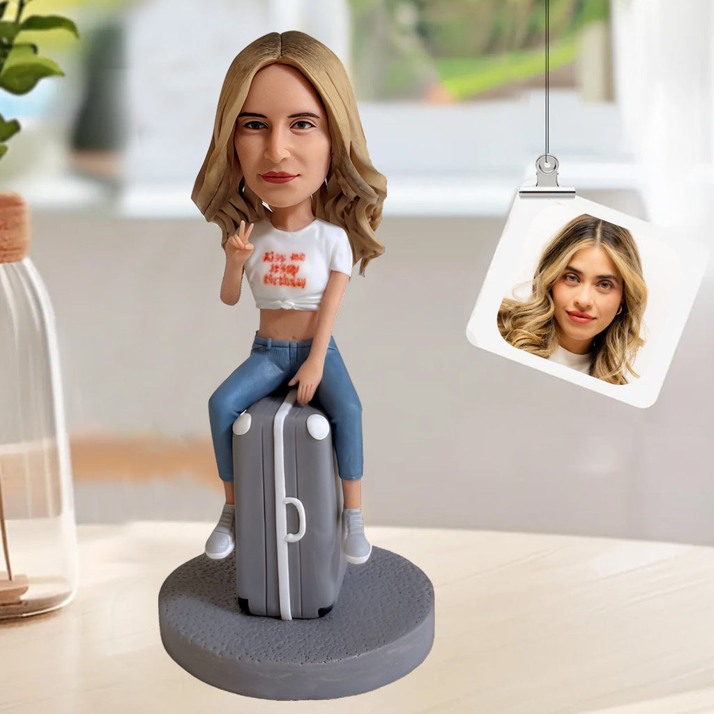 Figurine à tête branlante personnalisée posée sur une valise