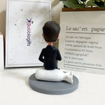 Figurine à tête branlante personnalisée en costume, assise sur un sac d'argent